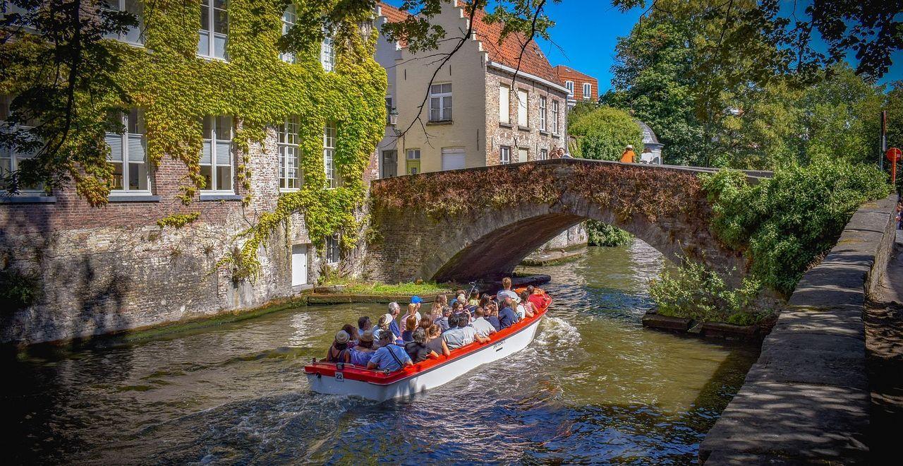 Tourists on a boat ride under a historic bridge in Bruges canal.