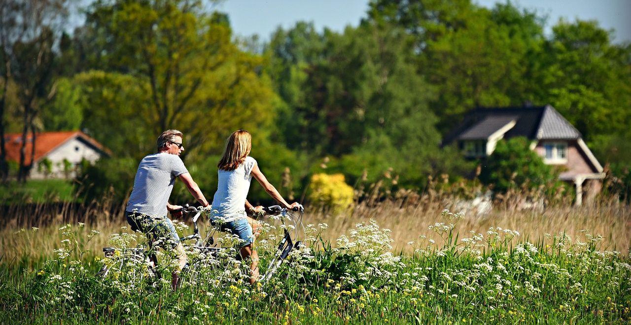 Couple cycling through a lush green meadow in the countryside.