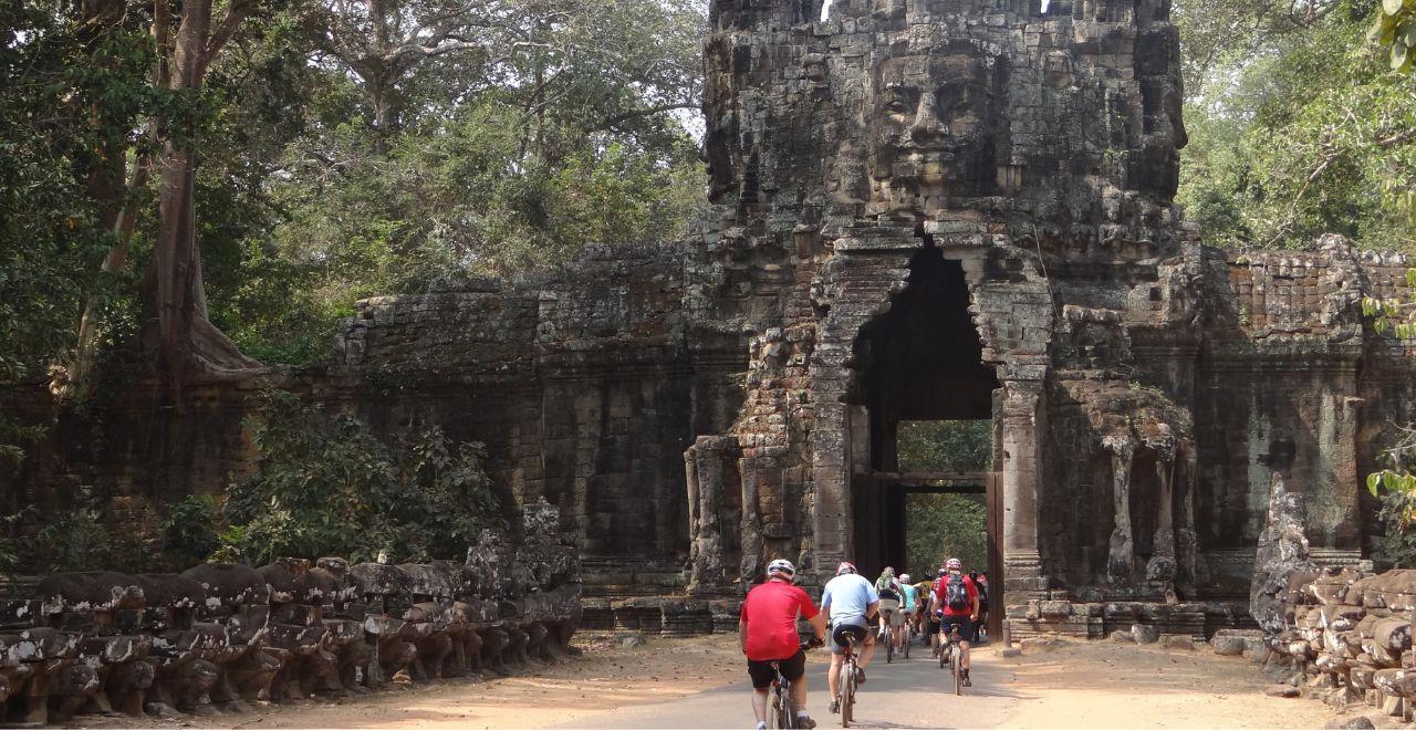 Cyclists entering an ancient stone gate in Angkor Wat