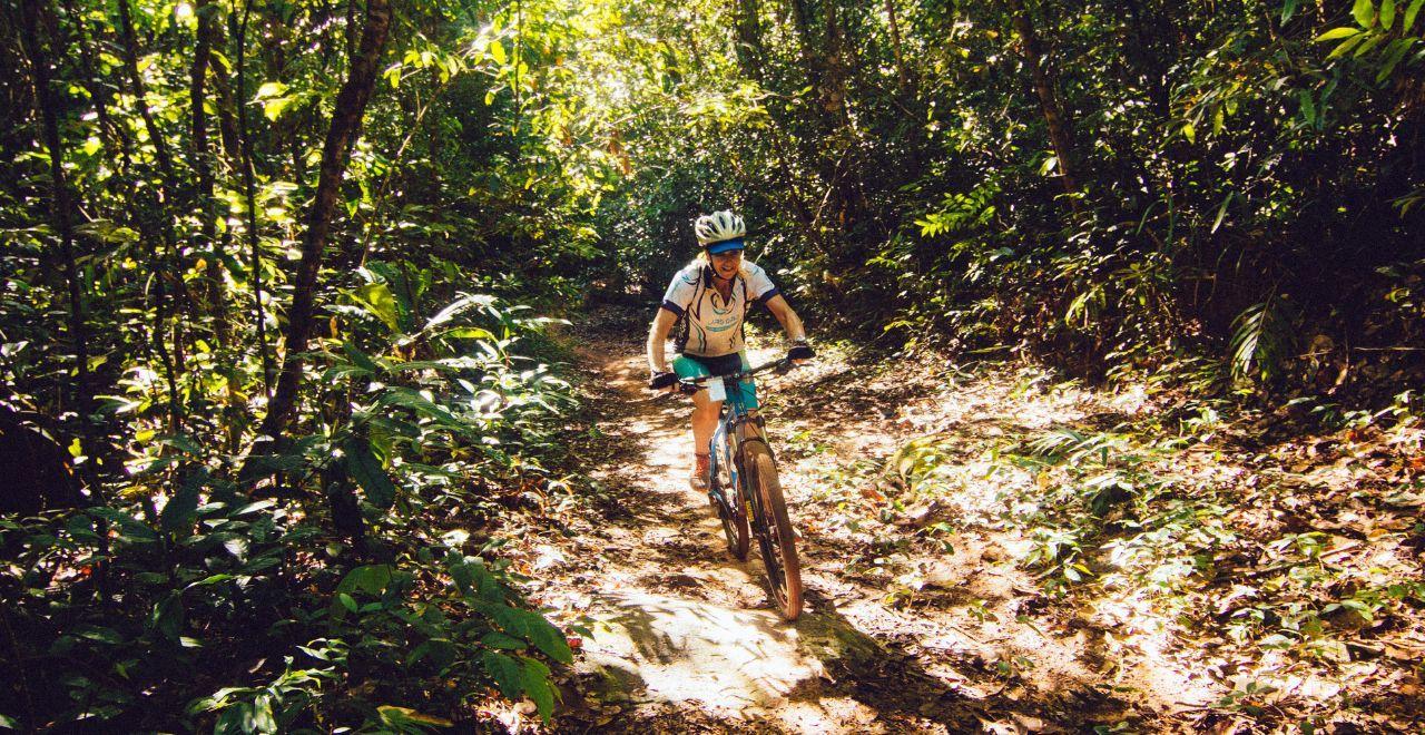 Cyclist riding through a dense, lush forest trail
