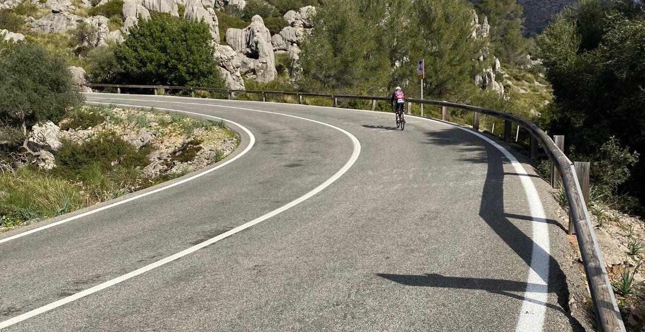 Single cyclist on road approaching a bend on a Mallorcan road