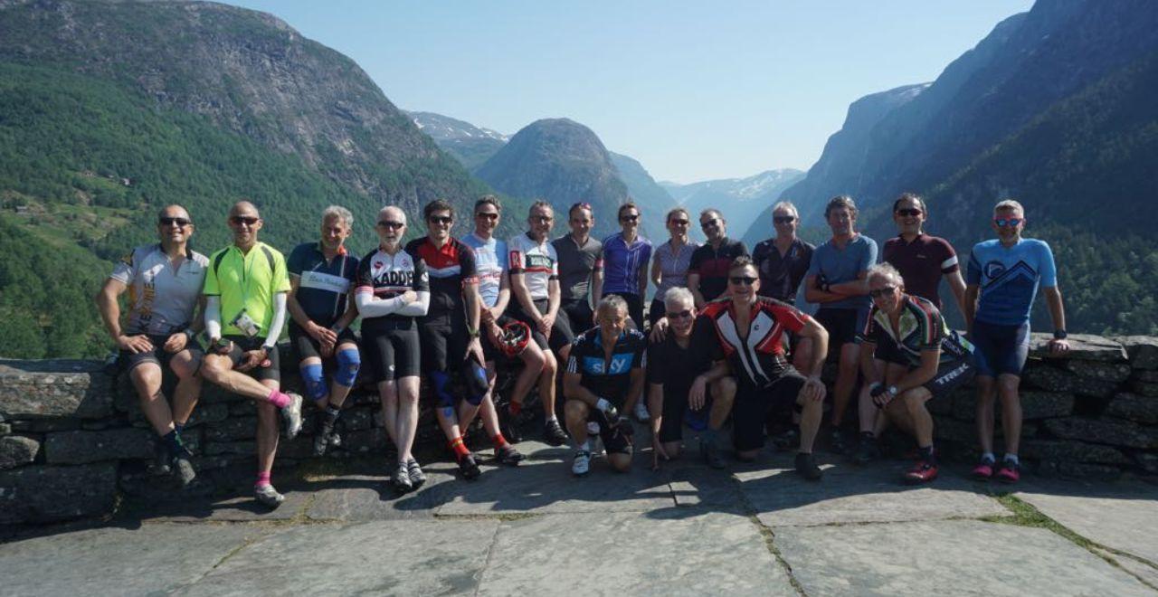 Group of cyclists posing with mountains in the background.