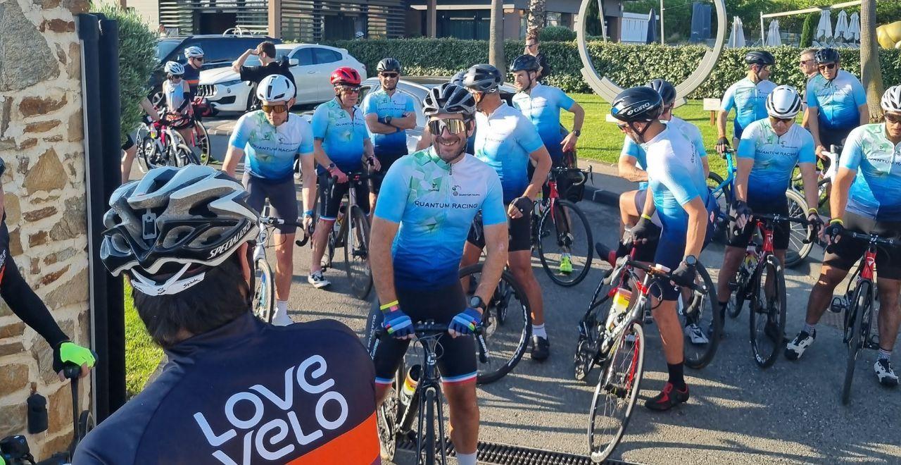 Cyclists in blue jerseys and one in a black "Love Velo" jersey preparing for a ride.