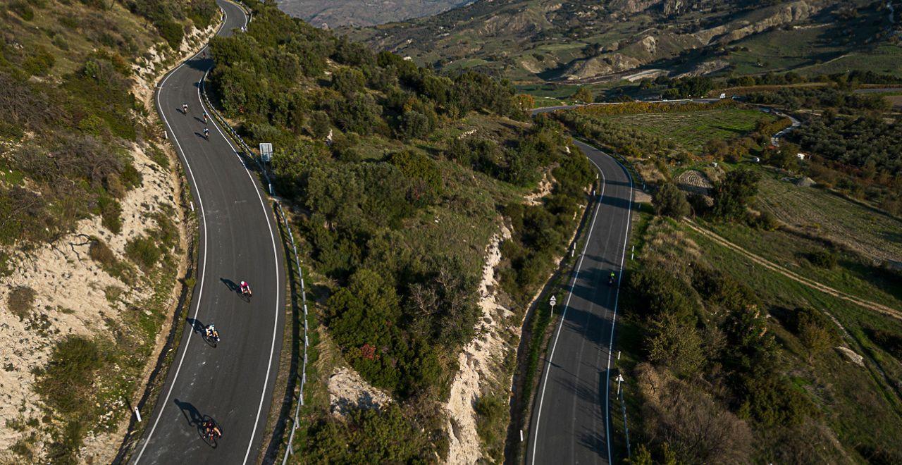 Breathtaking aerial view of cyclists on a winding mountain road in Cyprus, showcasing the island's diverse and rugged terrain ideal for adventurous rides