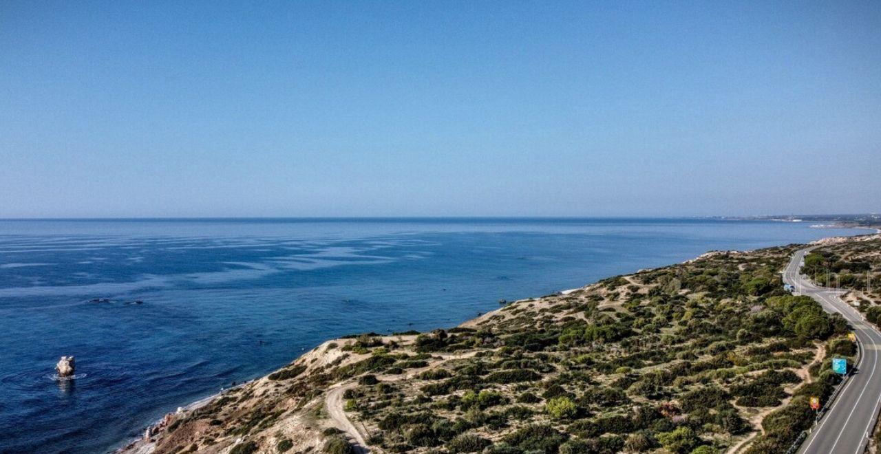 Serene morning cycling on a coastal road in Cyprus, offering unobstructed views of the deep blue Mediterranean and rocky shores