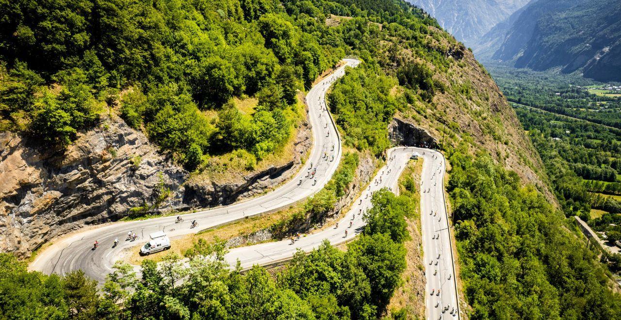 Aerial view of cyclists on a winding mountain road.