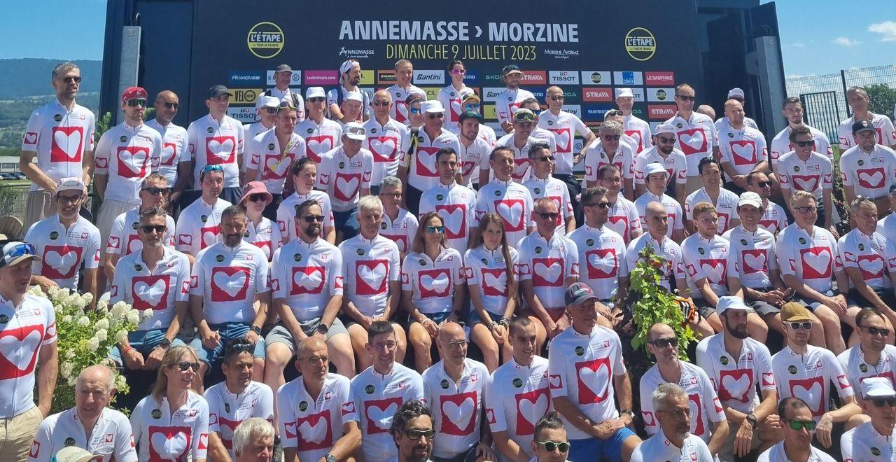 Large group of cyclists in heart jerseys posing for a group photo.