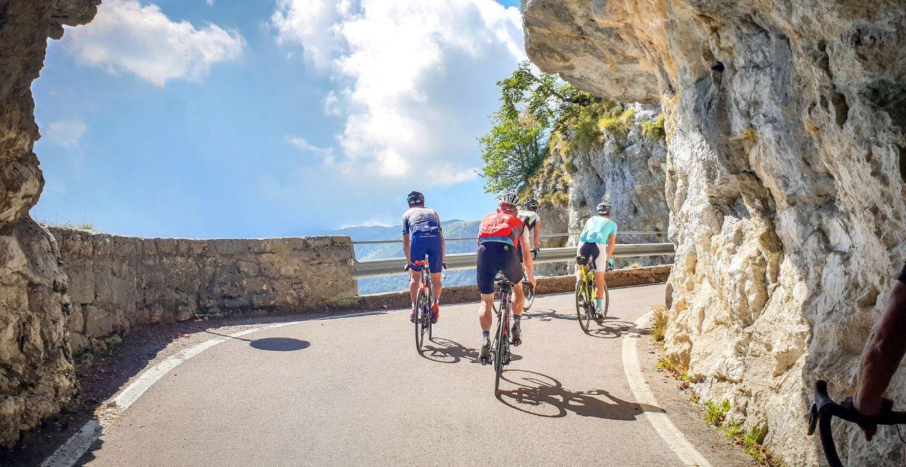 Cyclists riding through a mountain tunnel on a sunny day.