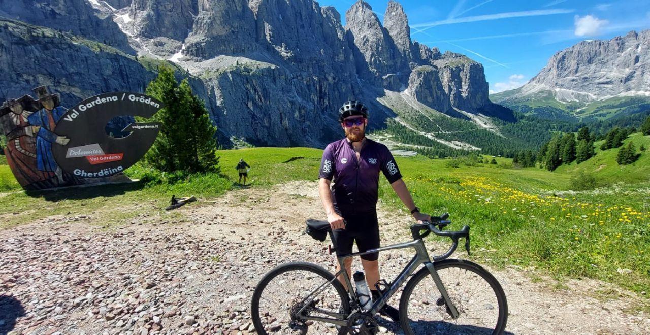 Cyclist posing with bike in front of Val Gardena Dolomites mountains.
