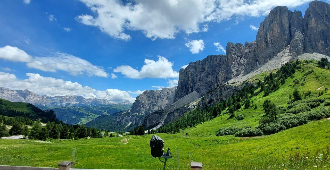 Scenic mountain view with lush green meadows and blue sky in the Dolomites.
