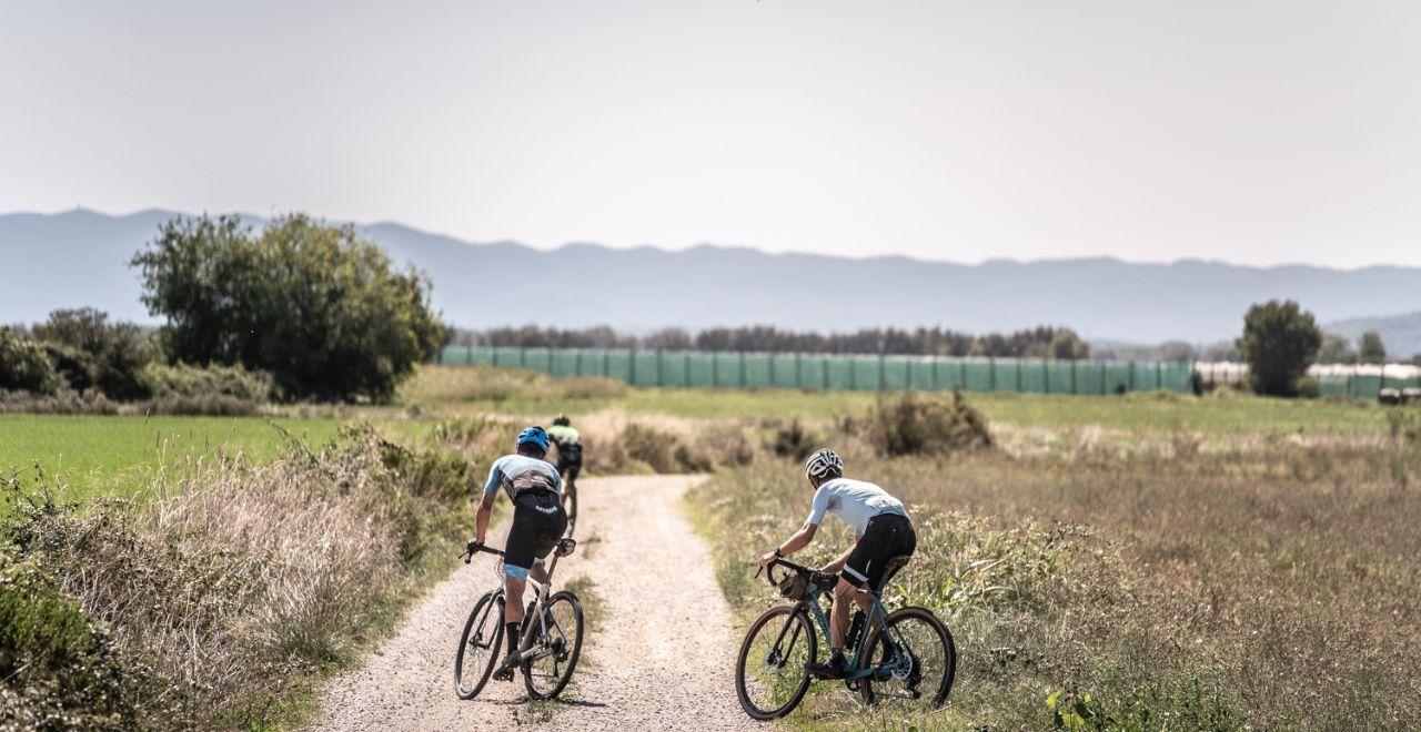 Cyclists on a dirt path with mountains in the background.