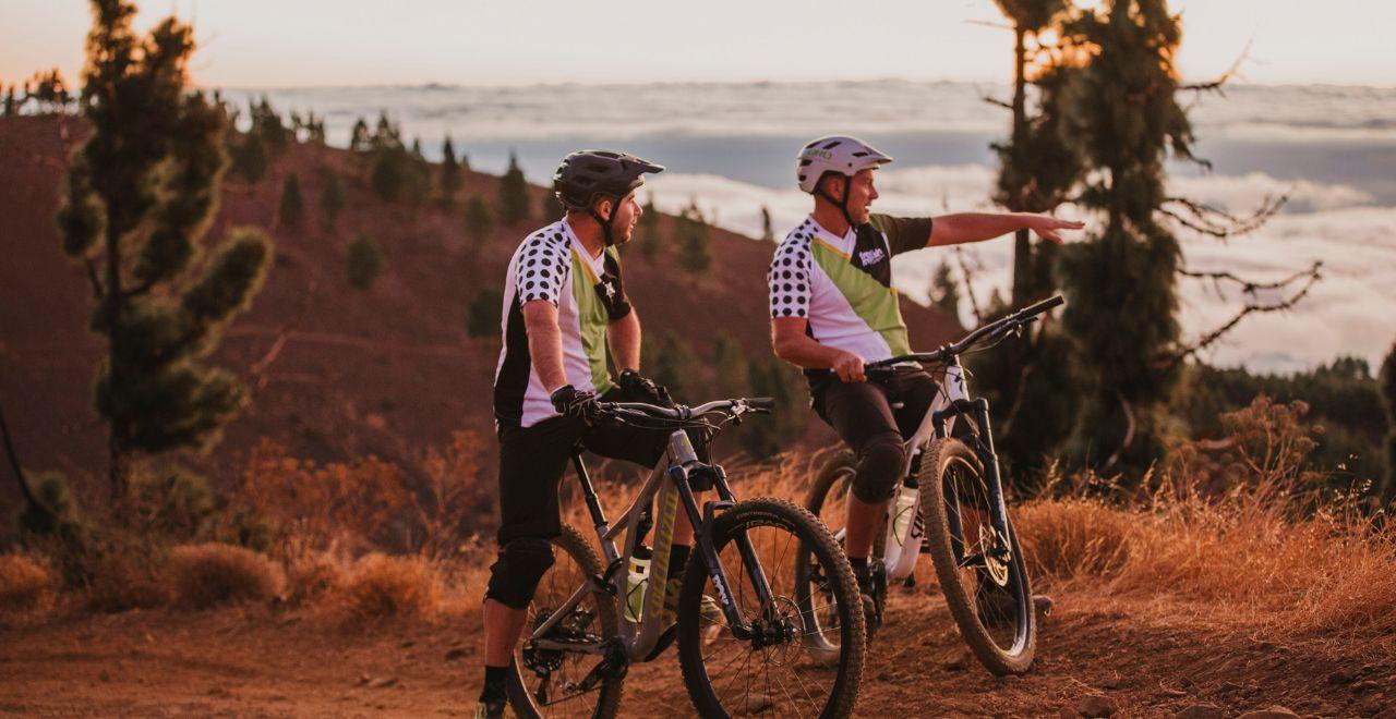 Two mountain bikers stopping to admire a scenic sunset view.