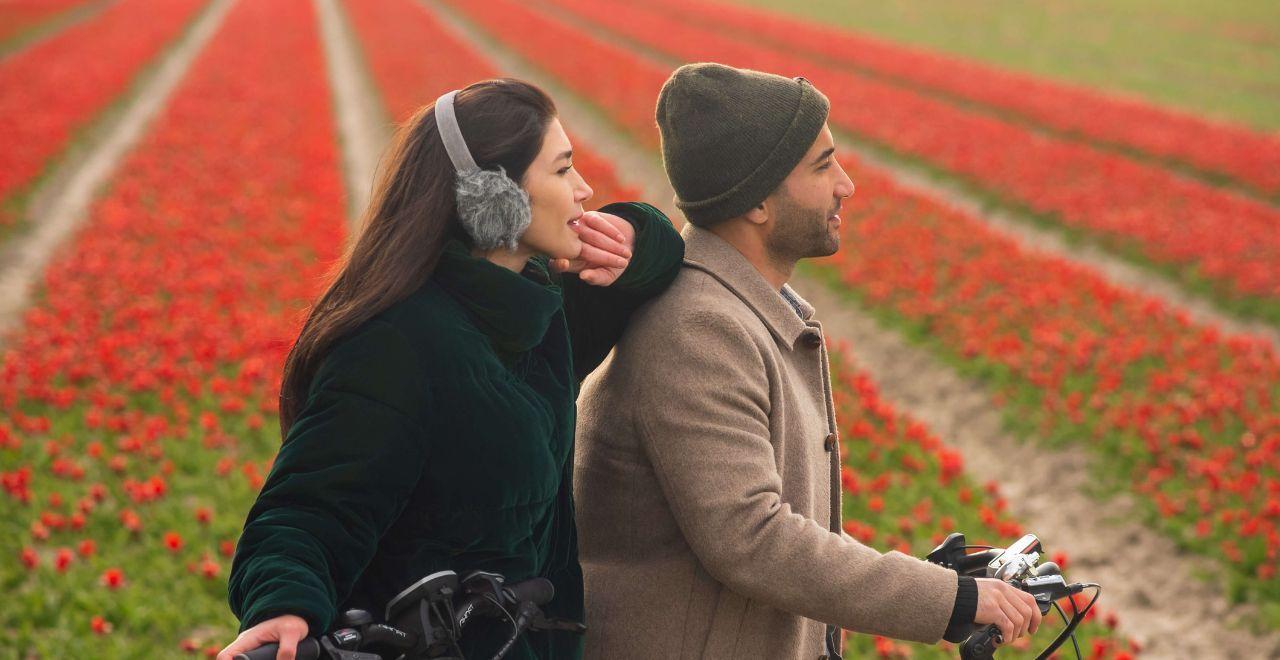 Couple enjoying a bike ride through a vast field of blooming red tulips