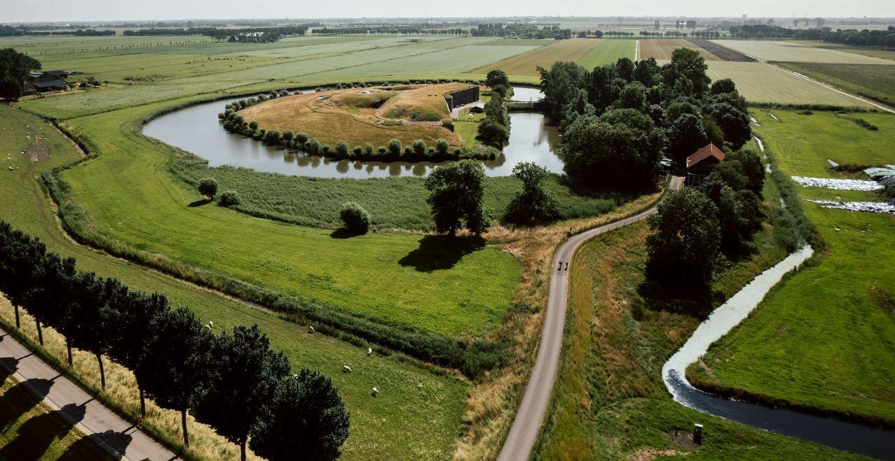 Aerial view of green Dutch countryside with winding river, fields, and a road with cyclists