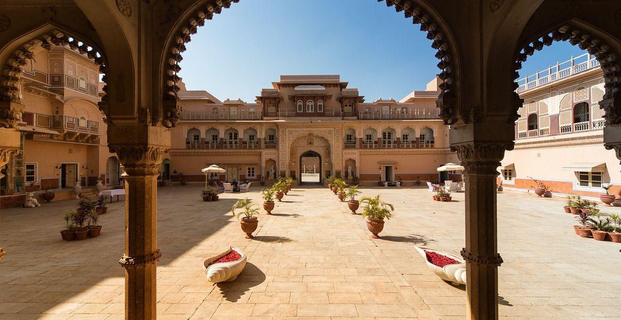 Spacious courtyard of a traditional Indian palace with arches and potted plants