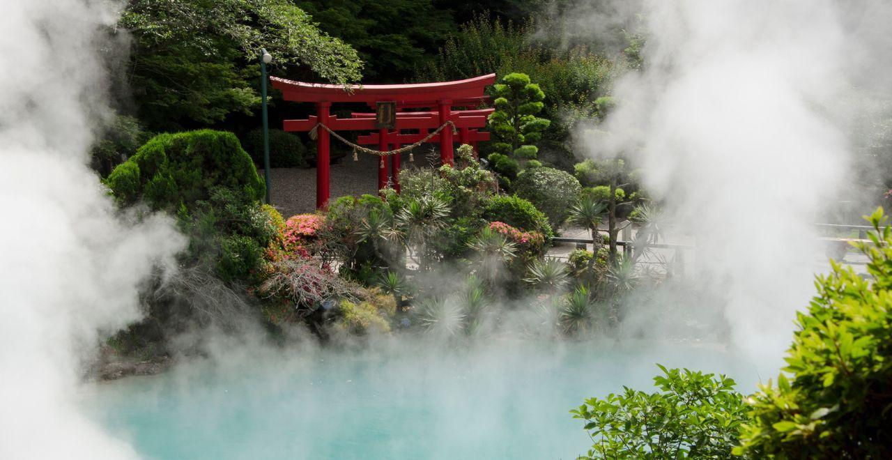 Japanese garden with red torii gate, steam rising from hot spring