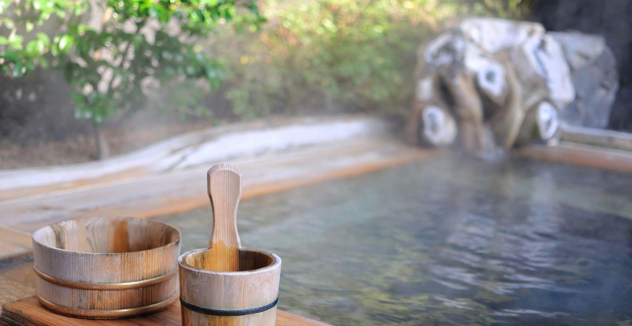 Outdoor hot spring bath with wooden buckets, steam rising