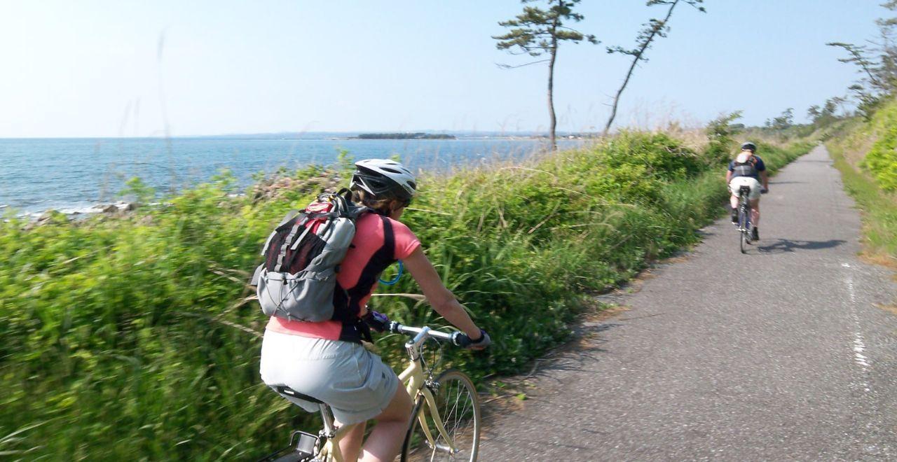 Cyclists riding along a coastal path with ocean views