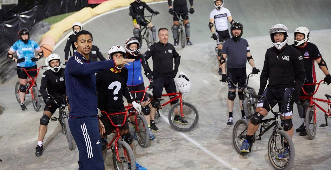 BMX riders listening to an instructor in a BMX track.