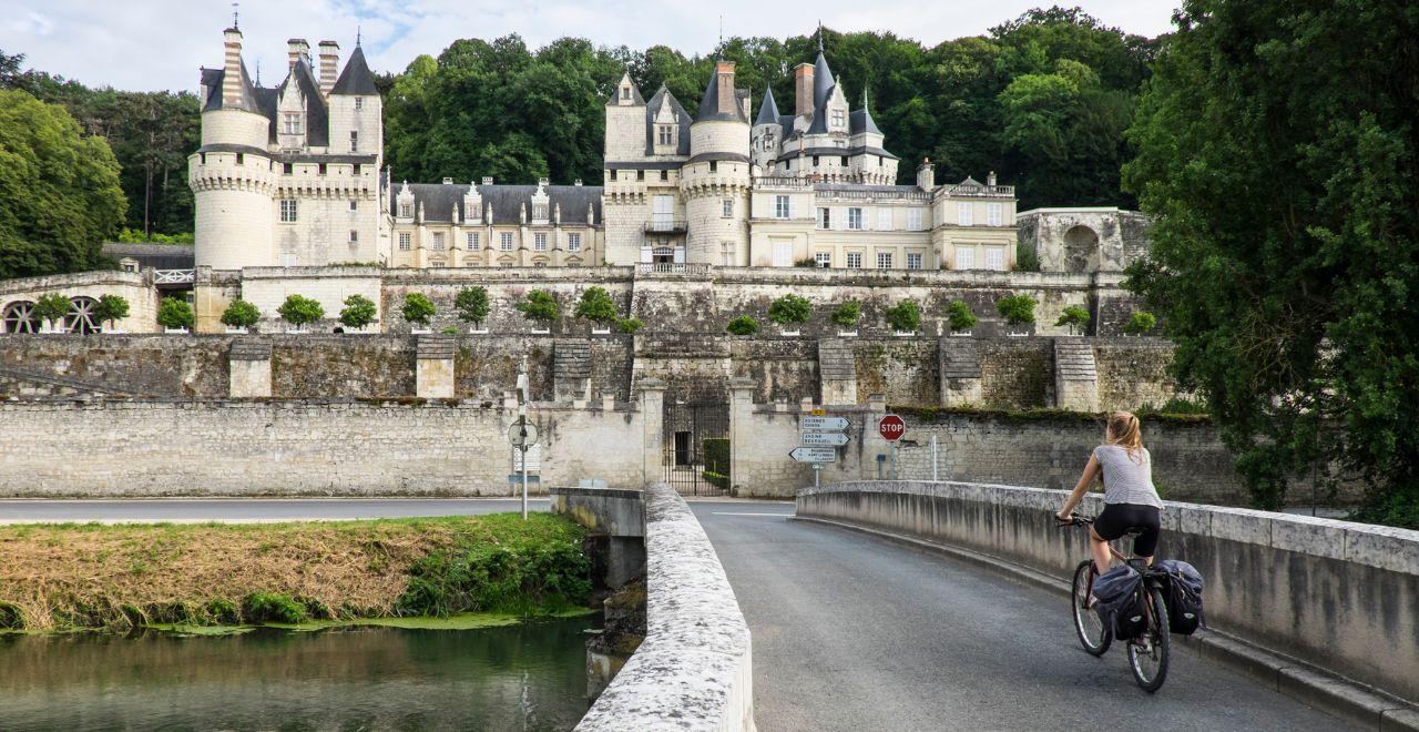 female cyclist approaching grand chateau in the Loire Valley