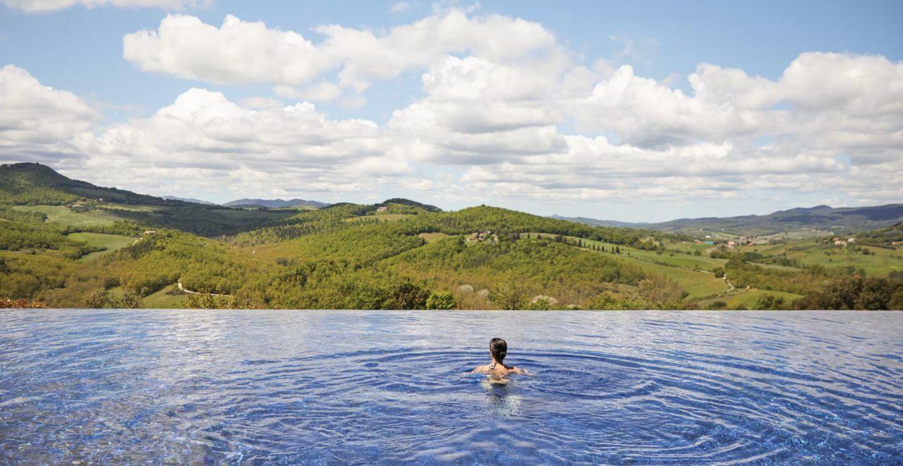 Person swimming in an infinity pool overlooking rolling hills
