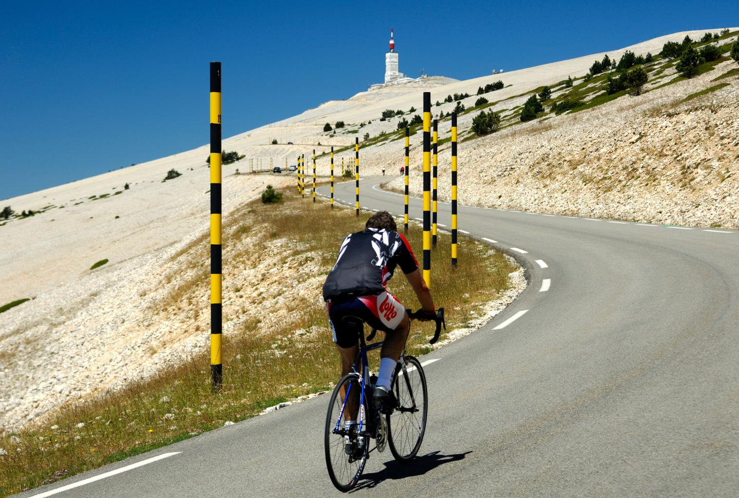 Cyclist ascending Mont Ventoux with a view of the iconic summit tower in the background.