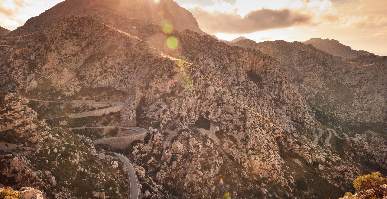 Scenic mountain road with hairpin turns during sunset.