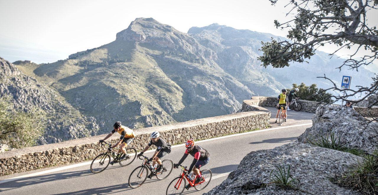 Cyclists riding along a scenic mountain road with a view.