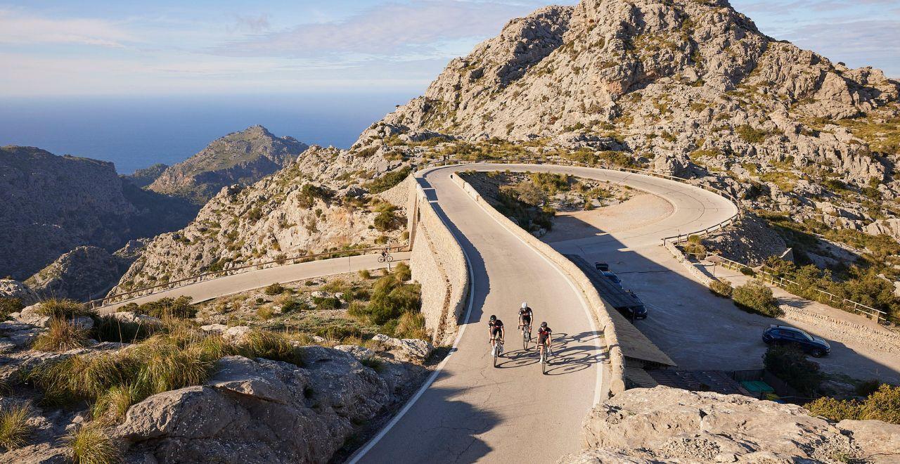 Cyclists riding on a winding mountain road with sea views.