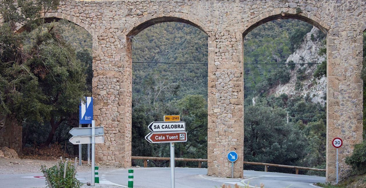 Stone arch bridge and road signs for Sa Calobra and Cala Tuent.