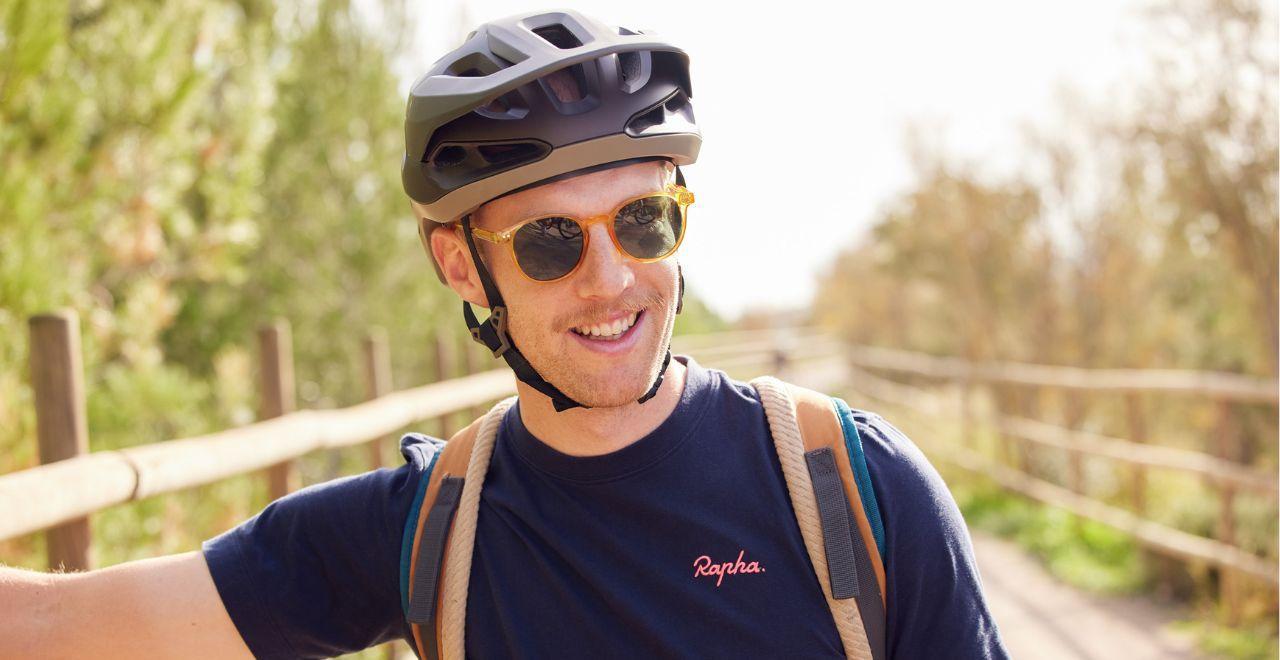 Smiling man with sunglasses and helmet posing with his bike.