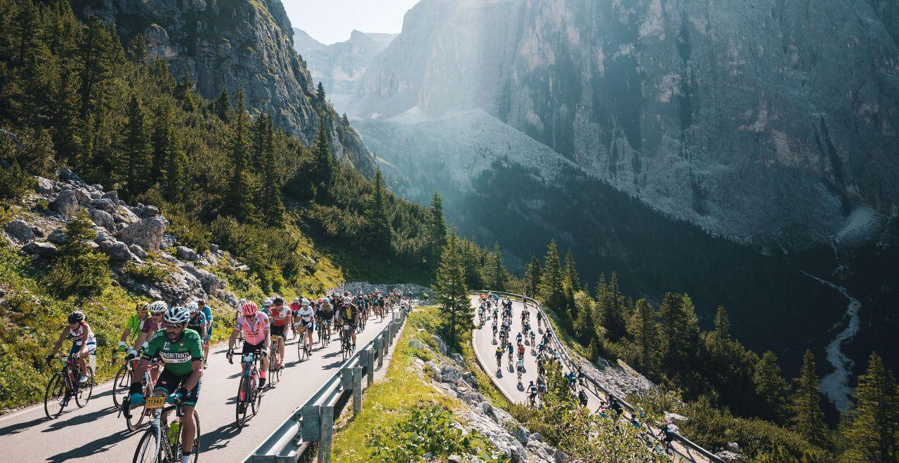 Cyclists riding uphill through mountain scenery during a race.