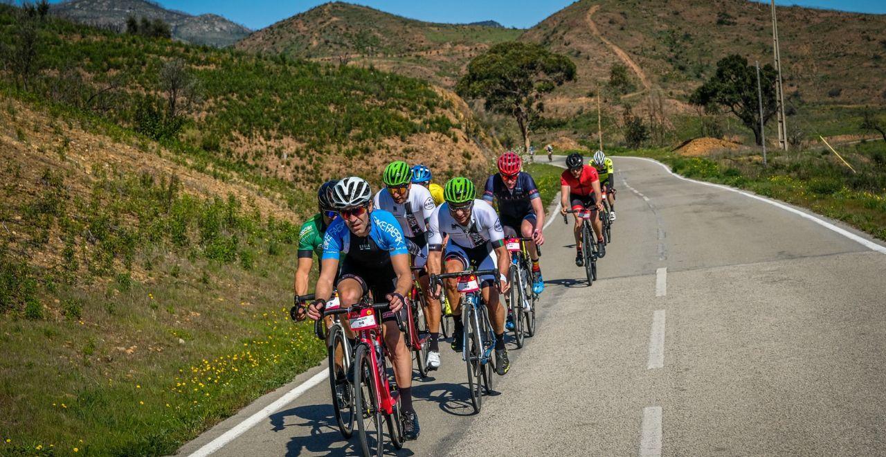 Cyclists ascending a mountain pass with a stunning view of rolling hills in the background, capturing the essence of an exhilarating group ride.