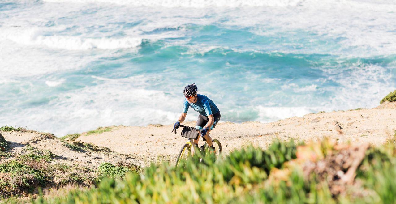 Cyclist climbing a coastal hill with ocean background