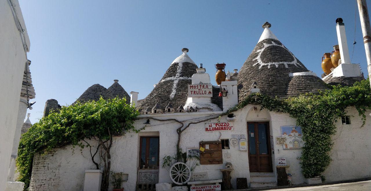 Traditional trulli houses with conical roofs and green vines in Alberobello.