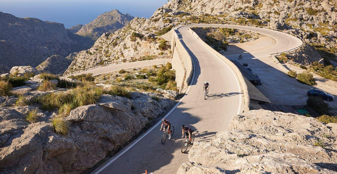 Cyclists riding on a winding mountain road in Mallorca.