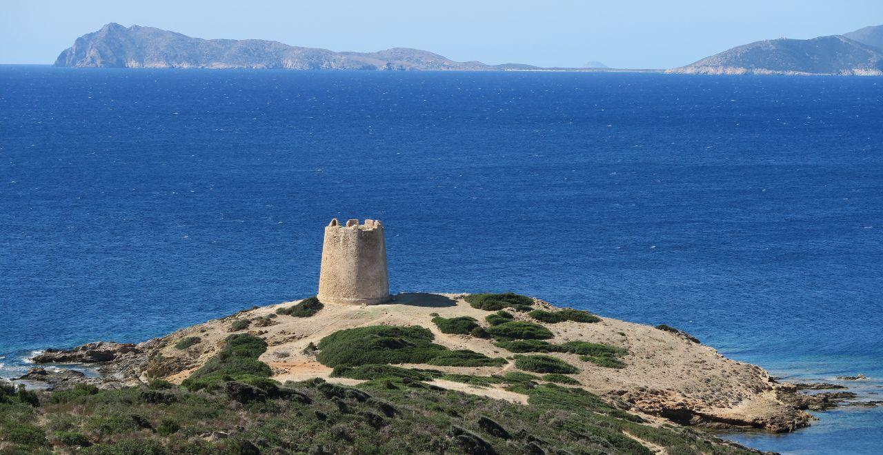 Coastal watchtower on a rocky hill with blue sea and distant islands.