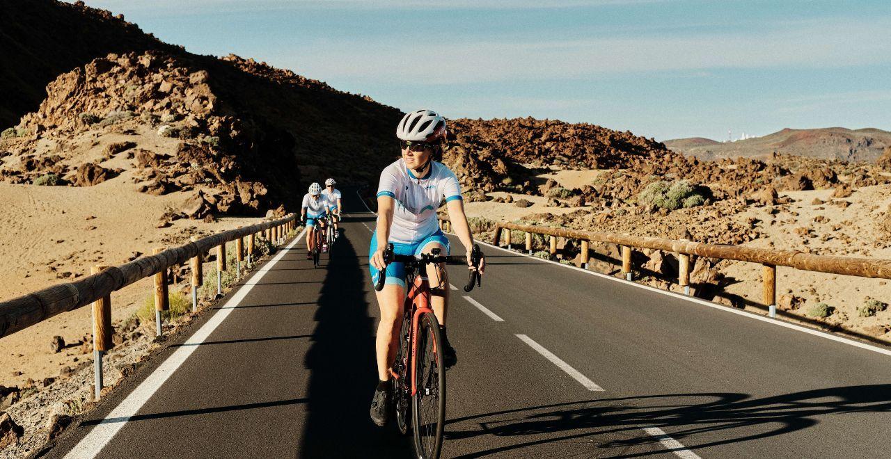 Female cyclist leading a group on a road in Teide National Park, Tenerife, surrounded by rocky and desert-like terrain