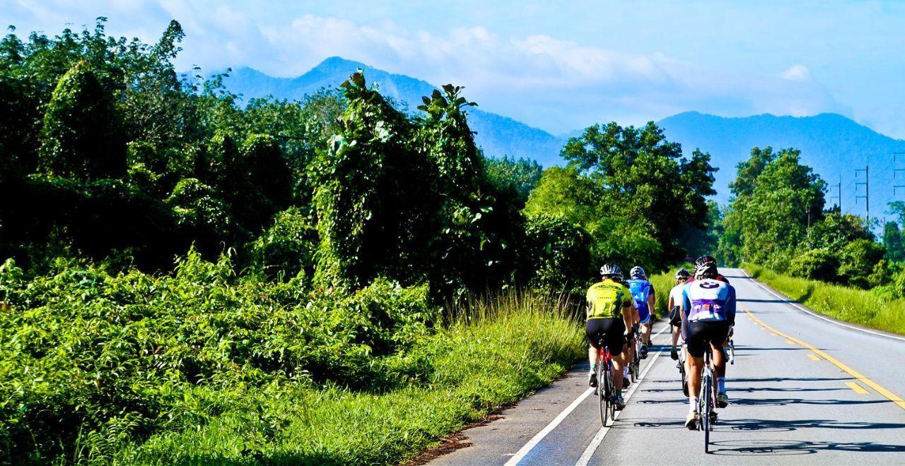 Group of cyclists riding on a rural road, mountain scenery