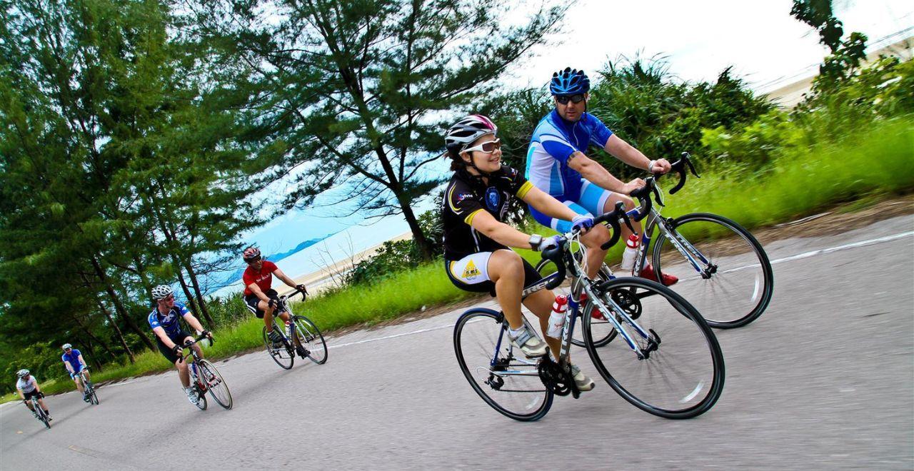 Group of cyclists riding on a coastal road with ocean view