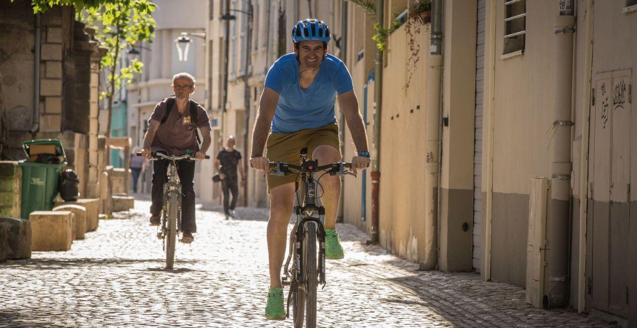 Cyclists riding on a cobblestone street.