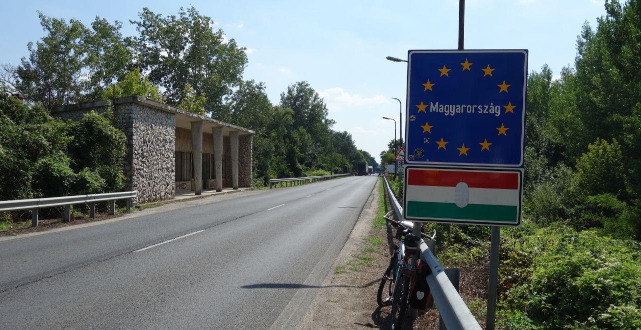 Roadside view of a sign indicating the border of Hungary with a bike resting against the guardrail