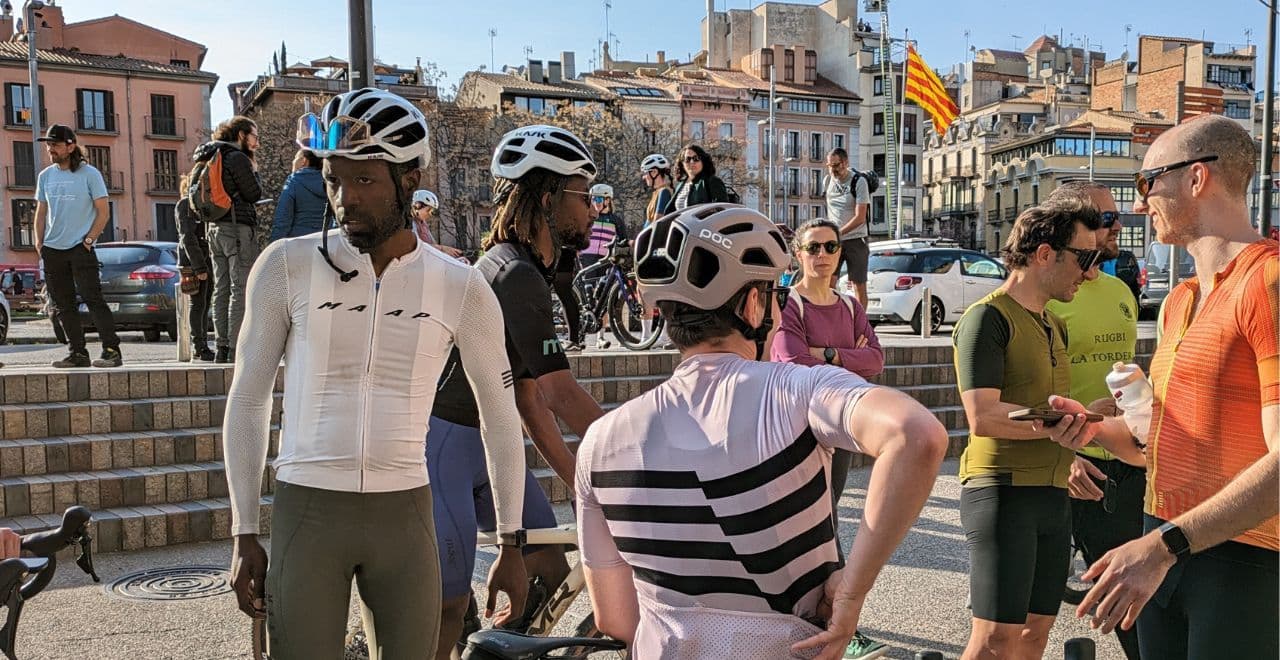 Cyclists in a town square talking and preparing for a ride.