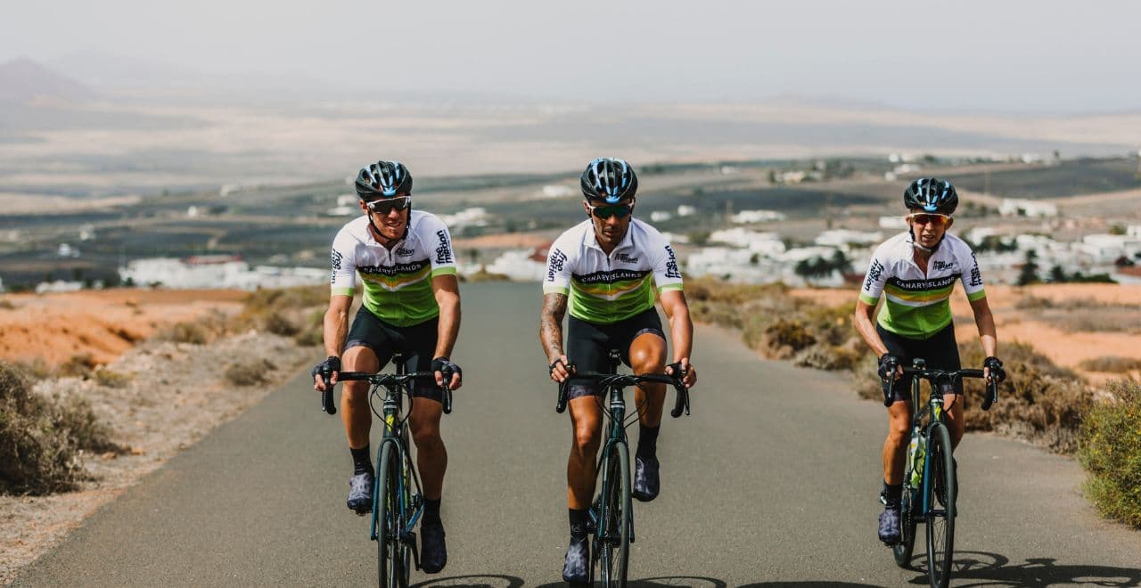 Cyclists riding on a road overlooking a vast landscape with villages.