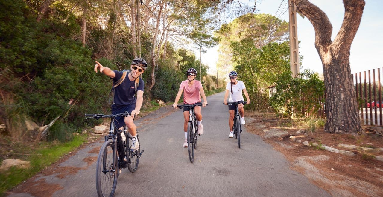 Cyclists riding on a road, one pointing direction.