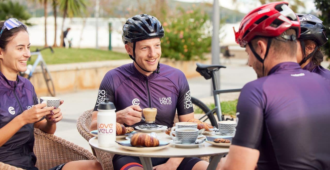 Cyclists enjoying coffee and pastries at an outdoor cafe.