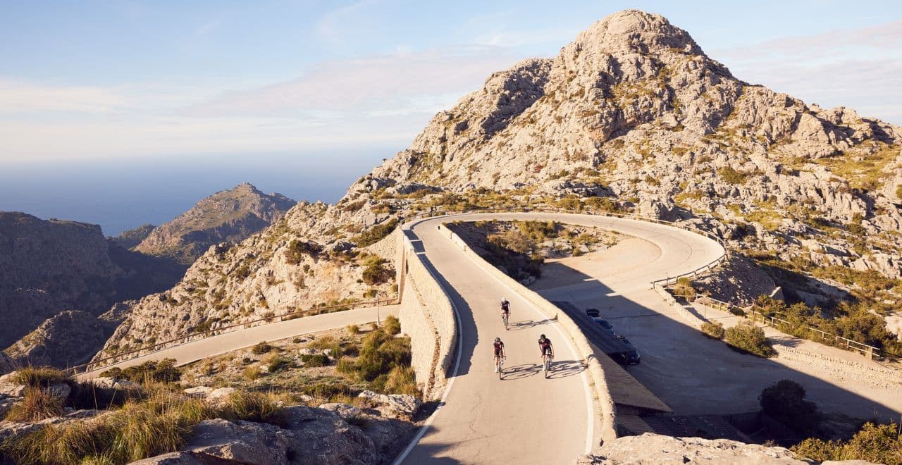 Group of cyclists on a curvy mountain road with sea view.