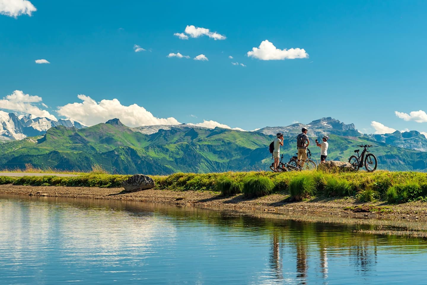 Group of cyclists taking a break by a mountain lake with scenic views.