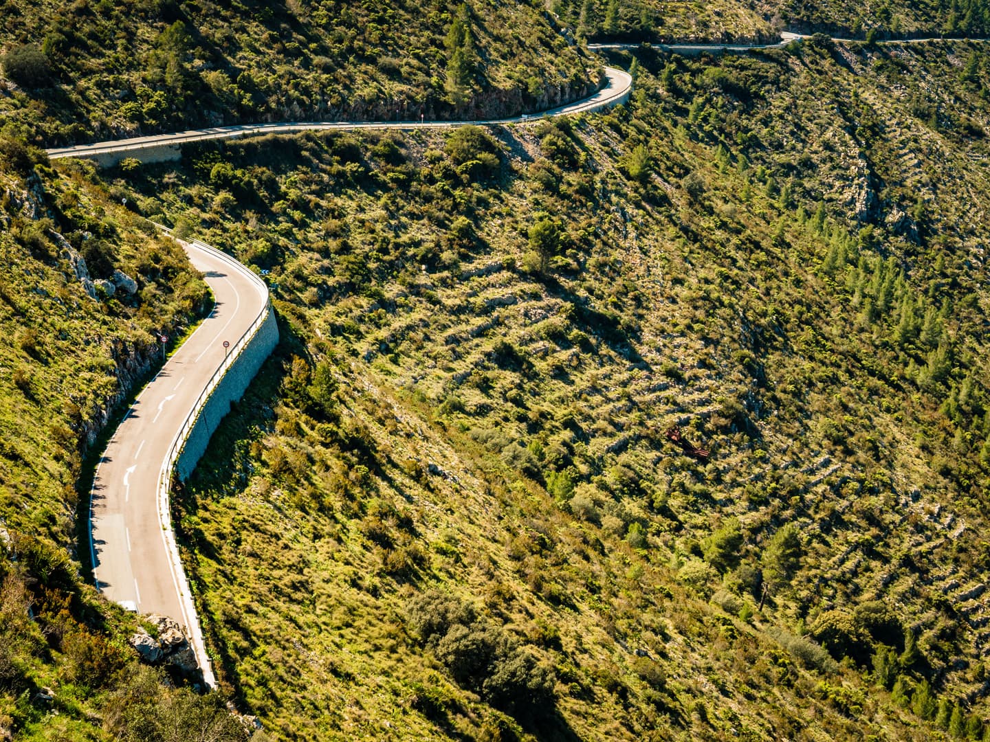 A winding road through the green hills of Coll de Rates in Costa Blanca, Spain, ideal for cyclists seeking a scenic and challenging climb.