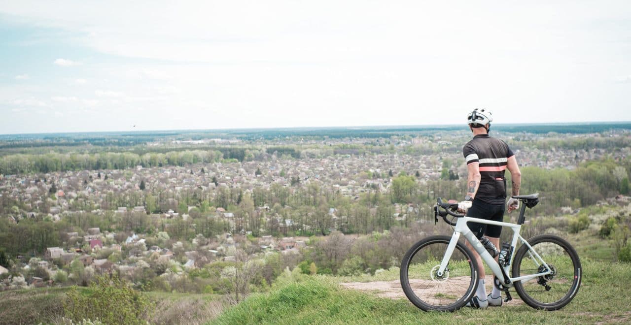 Cyclist with white gravel bike overlooking scenic town landscape